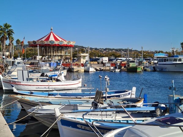 A marina with boats docked, a carousel, and a clear sky.