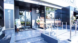 A modern hotel entrance with a glass facade, a signboard, and a staircase leading to the entrance. - Hotel Livemax, Hashima Ekimae (Hashima)