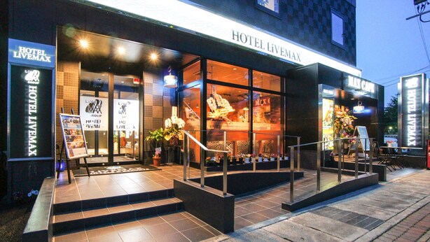 A hotel entrance with a glass facade, steps leading up to the entrance, and a sign reading "HOTEL LIVEMAX". - Hotel Livemax, Hashima Ekimae (Hashima)