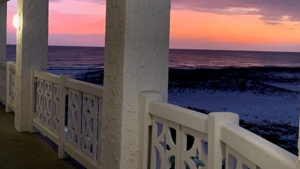 A coastal view from a balcony with white railings and columns, overlooking the sea during sunset. - El Matador 255 - FREE TICKETS!! Your stay includes free tickets to many area attractions! (Fort Walton Beach)