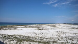 A beach with white sand and sparse vegetation under a clear blue sky. - El Matador 255 - FREE TICKETS!! Your stay includes free tickets to many area attractions! (Fort Walton Beach)