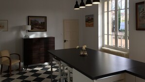 A kitchen with a black countertop, a chair, a cabinet, and a window with a view of the outside. - Renovated, spacious Les toiles à Elise mansion with swimming pool (Saint-Geniès-De-Comolas)