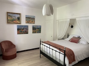 Un dormitorio con una cama, una silla y cuatro cuadros en la pared.