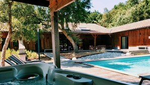 Et område med jacuzzi, pool, træterrasse og udendørs møbler.