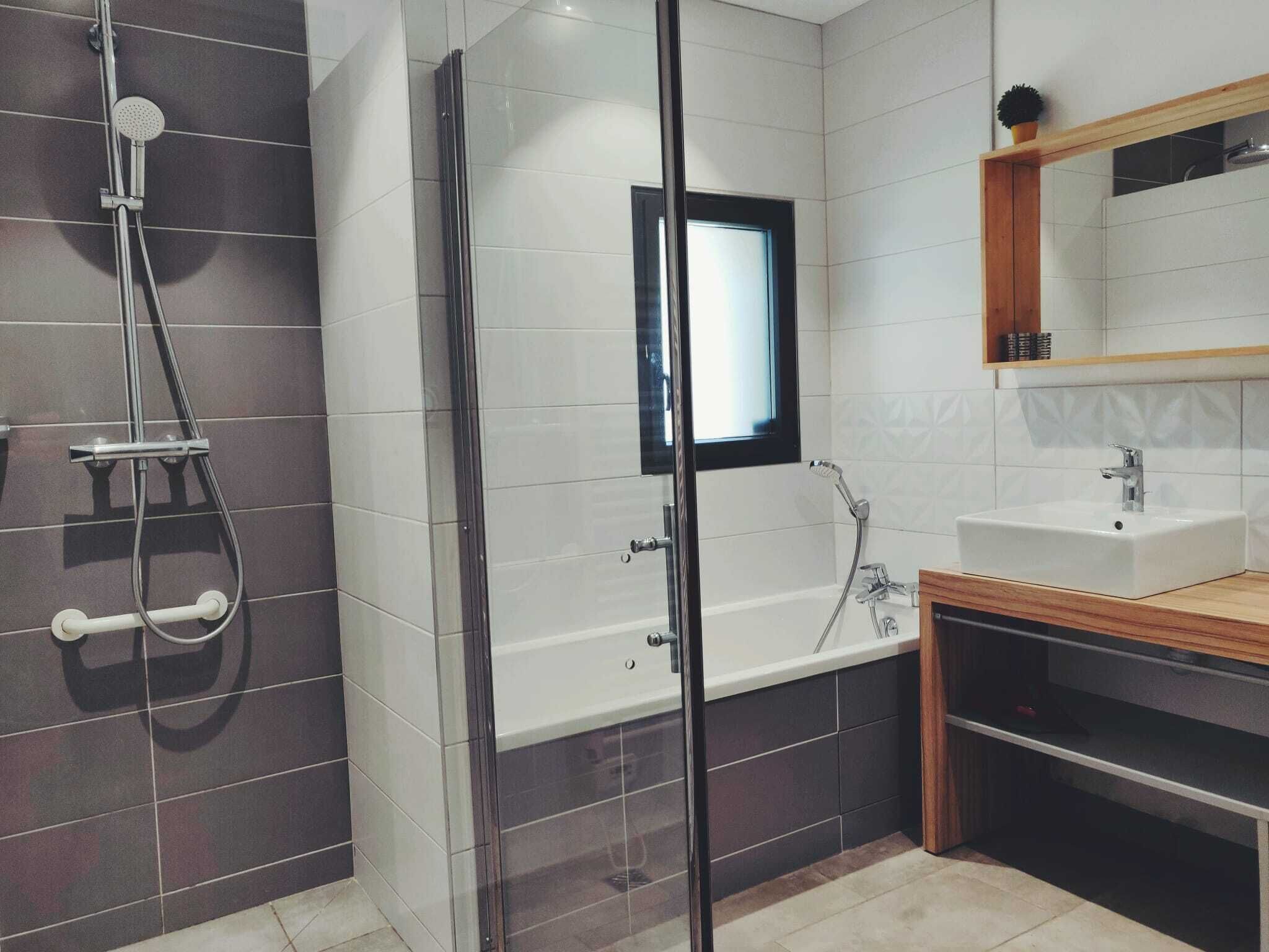 A modern bathroom with a glass-enclosed shower, a built-in sink, and a mirror above the vanity.