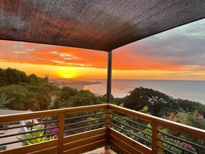 Un balcon offrant une vue sur le coucher de soleil sur l’océan.