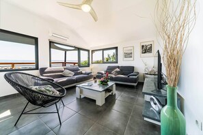 A modern living room with a sofa, a chair, a coffee table, and a television.