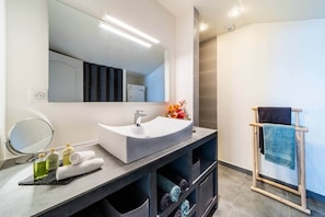 Un baño moderno con un lavamanos grande, espejo y barra para toallas.