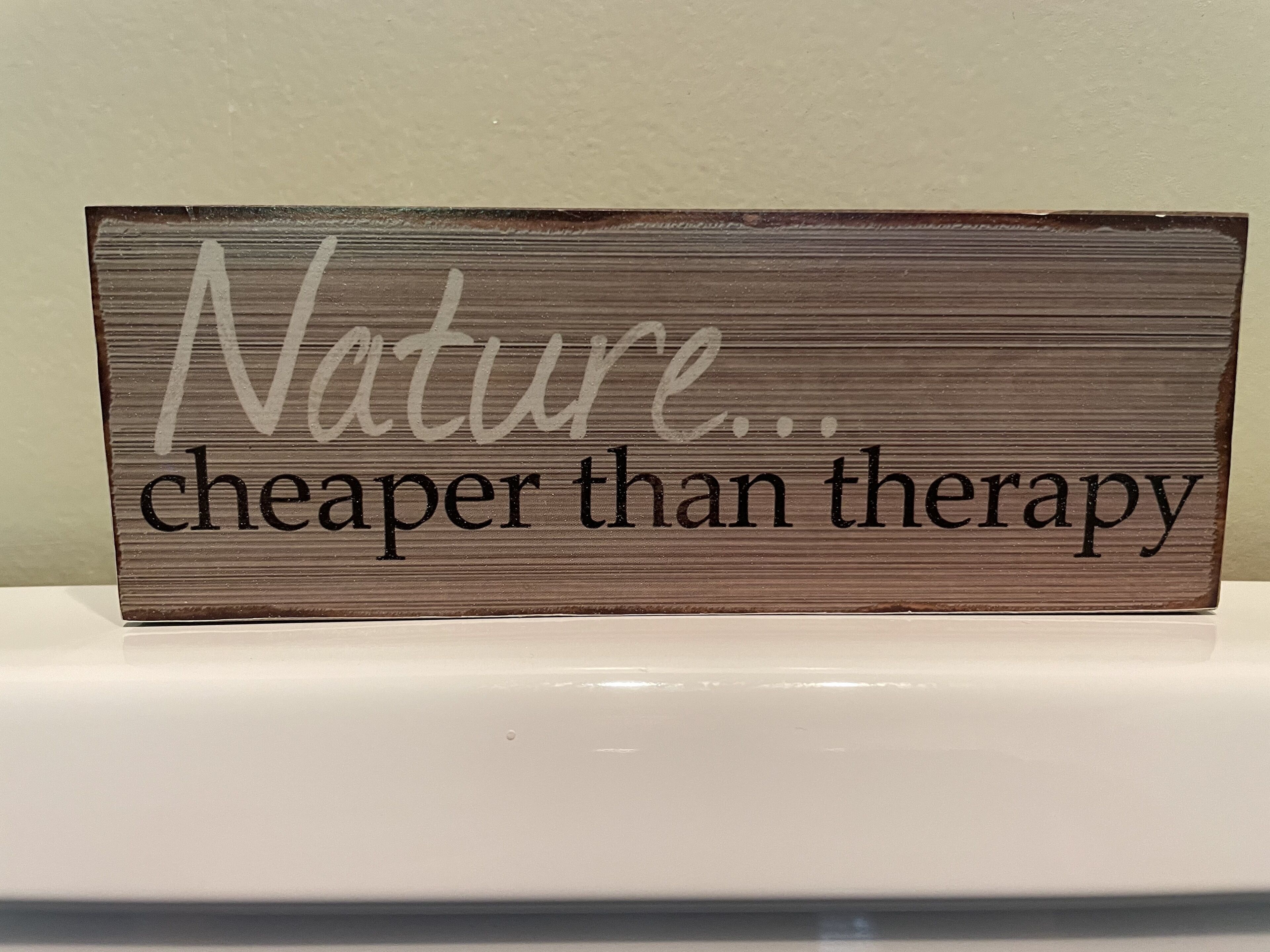 Un senyal de fusta amb el text 'Naturalitat... més barata que la teràpia.'