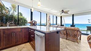 A modern kitchen with a large island, wooden cabinets, and a view of the ocean. - 101 - 2 bed/2 bath with A/C! Ground Floor Oceanfront with Breathtaking Views! (Kihei)