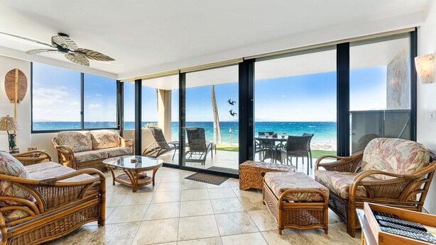 A spacious balcony with wicker furniture, large windows, and a view of the ocean. - 101 - 2 bed/2 bath with A/C! Ground Floor Oceanfront with Breathtaking Views! (Kihei)