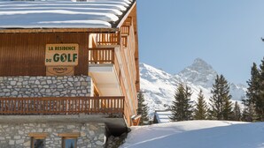 A mountain lodge with a sign reading "LA RESIDENCE DU GOLF maeva" and a snow-covered mountain in the background.