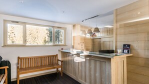 A wooden bench, a reception desk, and a window with a view of trees.