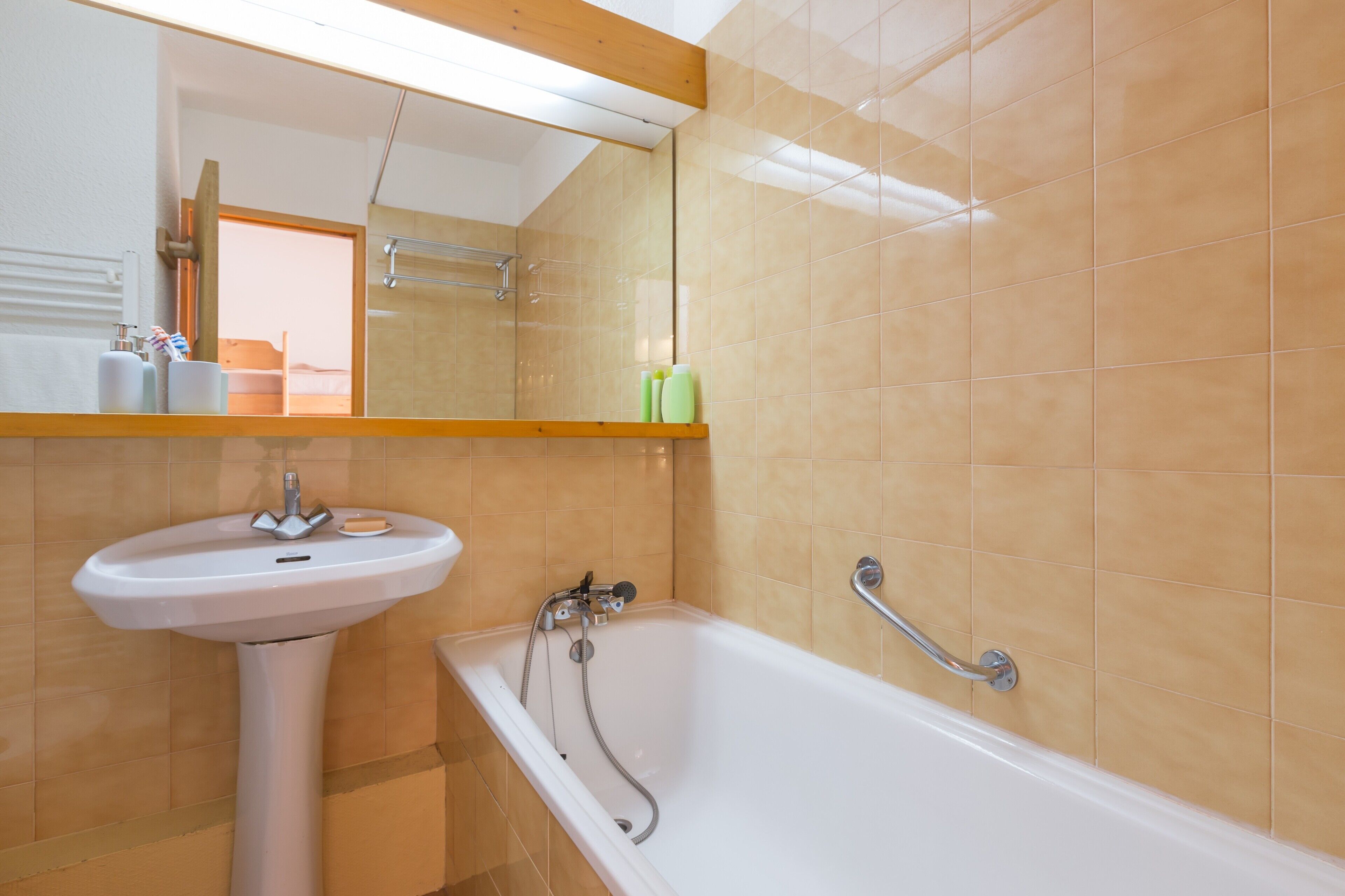Une salle de bain avec un lavabo blanc, une baignoire et un miroir au-dessus du lavabo.