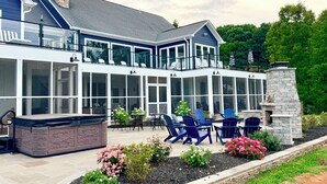 Ein modernes Haus mit überdachter Terrasse, Sitzgelegenheiten im Freien und einem Kamin aus Stein.