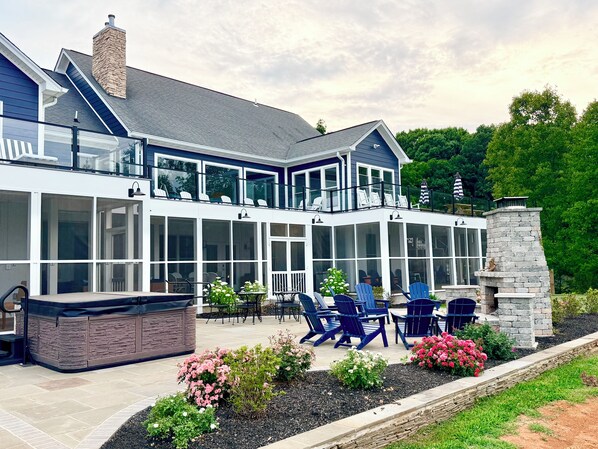 A modern house with a covered patio, outdoor seating, and a stone fireplace. - Sunrise at Lake Anna: Boathouse, Pickleball, Hot Tub, Golf, Sleeping Porch, Game (Mineral)
