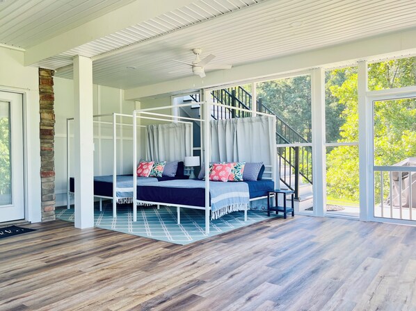 A spacious room with a four-poster bed, a staircase, and large windows offering a view of greenery. - Sunrise at Lake Anna: Boathouse, Pickleball, Hot Tub, Golf, Sleeping Porch, Game (Mineral)