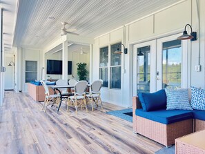 Ein überdachter Patio-Bereich mit Esstisch, Stühlen und einer Couch.