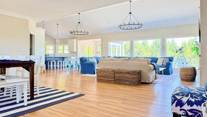 Ein geräumiger Wohnbereich mit großem Sofa, Esstisch und einer Küche im Hintergrund.