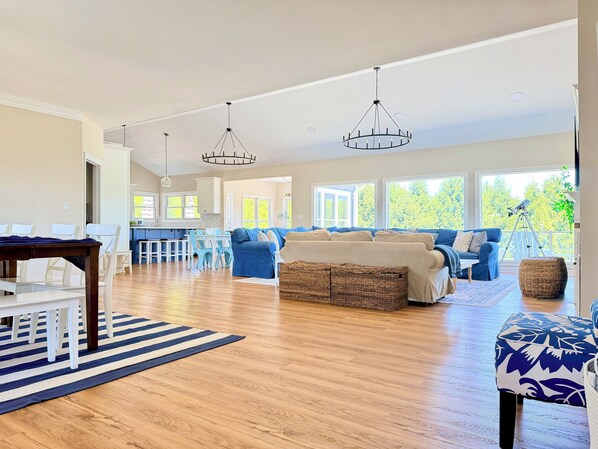 A spacious living area with a large sofa, a dining table, and a kitchen in the background.