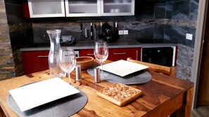 A wooden dining table with a white plate, two wine glasses, and a silver salt shaker.