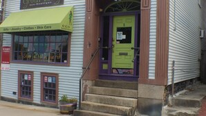 Un bâtiment à deux étages doté d’un auvent vert sur lequel est inscrit « Green Envy, boutique écologique », proposant des cadeaux, des bijoux, des vêtements et des produits de soins pour la peau.