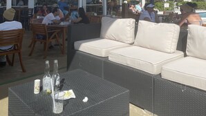 An outdoor seating area with wicker furniture, a bar, and a pool in the background. - Magnificent beach front condo with pool and restaurant/bar (Freeport)