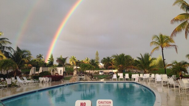 A swimming pool with lounge chairs and a sign indicating no lifeguard. - Magnificent beach front condo with pool and restaurant/bar (Freeport)