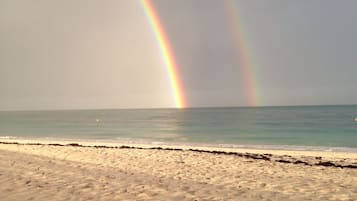 Una spiaggia con un arcobaleno sull'oceano.