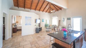 A spacious kitchen with a large island, wooden ceiling beams, and a view to the living area. - Fleur de Mer Villa Gracebay ( semi-detached) 2 bdrm -2 min drive from the beach! (Grace Bay)