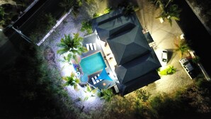 An aerial view of a property with a swimming pool, a covered patio, and several palm trees. - Fleur de Mer Villa Gracebay ( semi-detached) 2 bdrm -2 min drive from the beach! (Grace Bay)