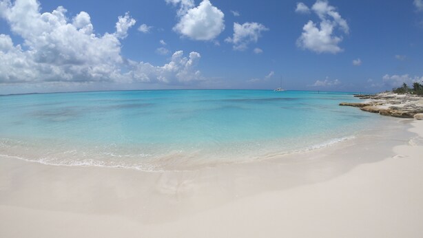 A beach with clear turquoise water, white sand, and scattered rocks. - Fleur de Mer Villa Gracebay ( semi-detached) 2 bdrm -2 min drive from the beach! (Grace Bay)