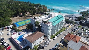 Un hôtel à plusieurs étages doté d’une piscine sur le toit, situé à proximité d’une plage et d’un court de tennis.