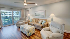 Ein geräumiges Wohnzimmer mit einer Couch, Sesseln, einem Couchtisch und einem Deckenventilator.
