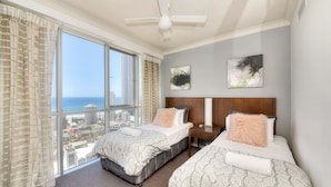 A hotel room with two beds, a large window with a city view, a ceiling fan, and artwork on the wall. - Deluxe Chevron Renaissance (Surfers Paradise)