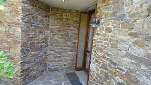 A stone-walled outdoor area with a metal door and a small window.