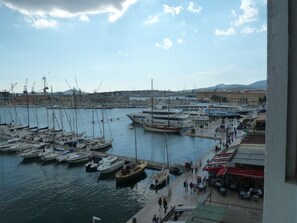 A marina with various boats docked, a pier with people walking, and buildings in the background. - Grand T1 Design of the port of Toulon. Magnificent views of the sea. (Toulon)