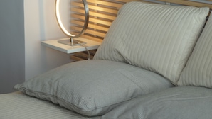 Un lit avec une tête de lit, une table de chevet avec un miroir et un oreiller.