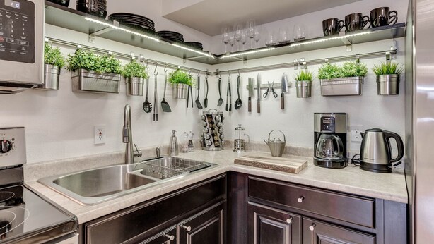 A modern kitchen with stainless steel appliances, a built-in sink, and a variety of utensils and cookware hanging on the wall. - View of the Yellowstone Valley  (Gardiner)