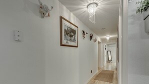 A hallway with white walls, a framed black and white photograph, decorative skulls, and a chandelier. - View of the Yellowstone Valley  (Gardiner)