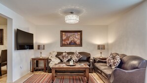 A living room with a flat-screen TV, a wooden coffee table, a leather sofa, and a patterned rug. - View of the Yellowstone Valley  (Gardiner)