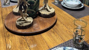 A dining table with a vase, candles, and a deer head mounted on the wall.