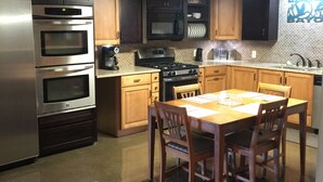 A kitchen with a stainless steel refrigerator, double ovens, a microwave, a stove, and wooden cabinets.