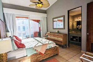 A bedroom with a bed, a dresser, a mirror, and a bathroom visible through an open door.