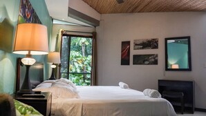 A hotel room with a bed, two bedside lamps, a ceiling fan, a window with curtains, and artwork on the walls. - Pool, Sauna, Hot Tub, Fruit Trees, Lush Gardens (Atenas)