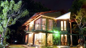 A two-story house with a balcony, large windows, and a well-lit exterior at night. - Pool, Sauna, Hot Tub, Fruit Trees, Lush Gardens (Atenas)