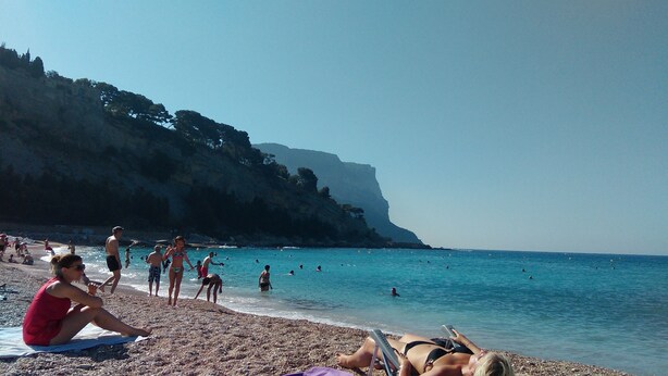 Une plage où des gens se prélassent au soleil et se baignent.