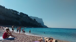 A beach with people sunbathing and swimming.