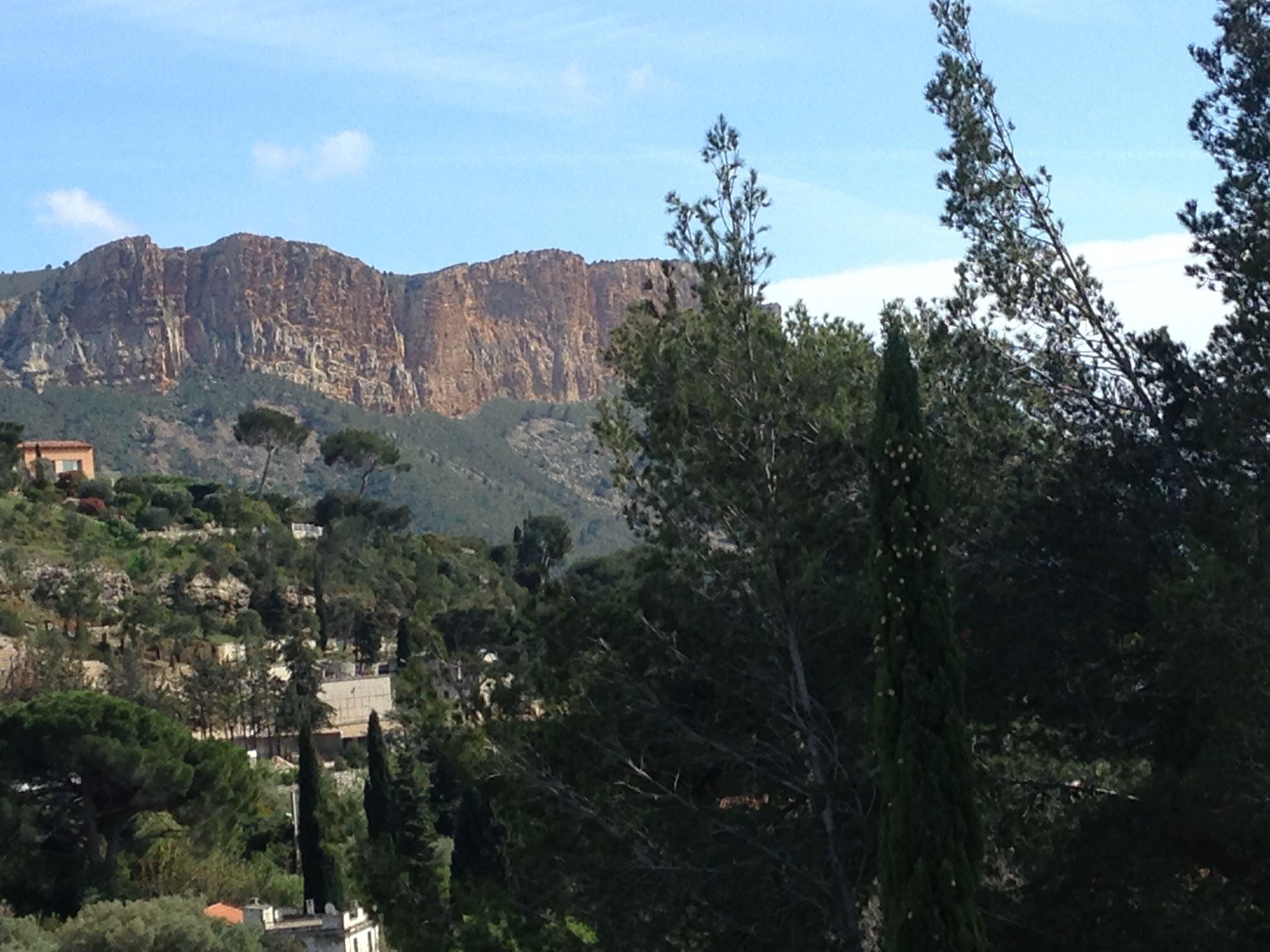 A mountainous landscape with a building in the foreground and a rocky cliff in the background.