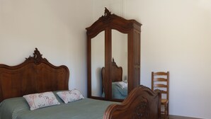A bedroom with a wooden bed, a mirror, and a wooden chair.